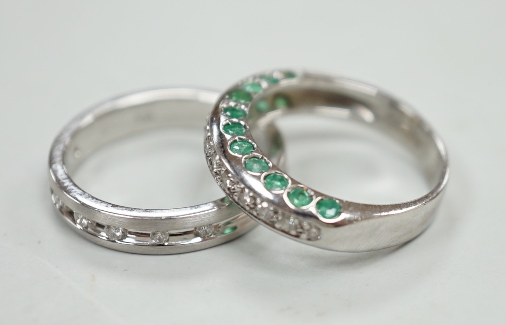An unusual modern 18ct white gold and thirteen stone diamond chip set half hoop ring, each side of the settling set with ten emeralds, size L and one other modern 18ct white gold and diamond chip set ring, size N, gross